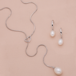 Juego de aretes con cadena tipo corbata y dije de rodio en forma de corazón con perla gota